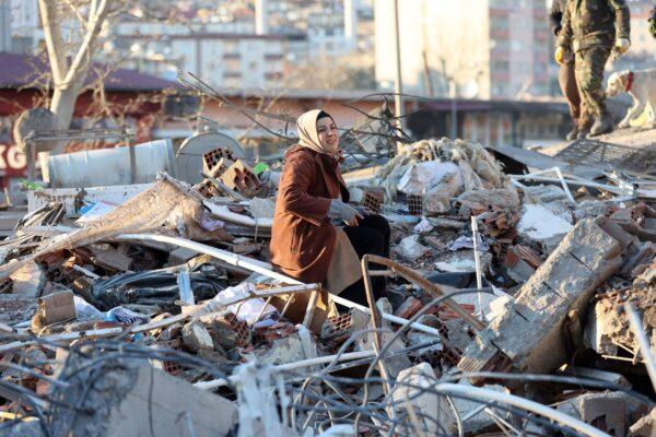 A woman sits on the rubble of a destroyed building in Kahramanmaras, southern Turkey, a day after a 7.8-magnitude earthquake struck the country's southeast, on Feb. 7, 2023. (Adem Altan/AFP via Getty Images)