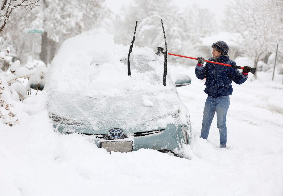 Cathy Morgan-Mace cleans snow and ice off her family's car during a snowstorm in Salt Lake City, Utah, on Feb. 22, 2023. (Kristin Murphy/The Deseret News via AP)