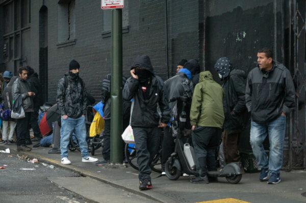 Homeless people stand on the sidewalk among alleged drug dealers in San Francisco on Feb. 23, 2023. (John Fredricks/The Epoch Times)