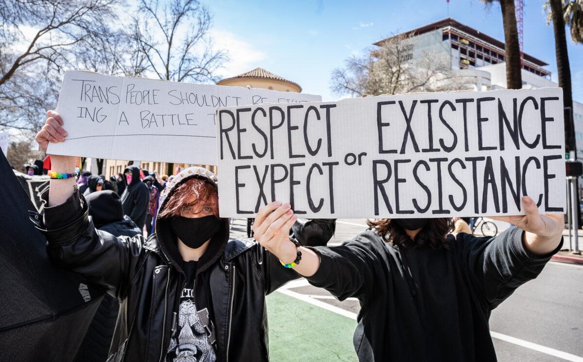 Transgender activists hold signs in front of the California State Capitol building in Sacramento, Calif., on March 10, 2023. (John Fredricks/The Epoch Times)