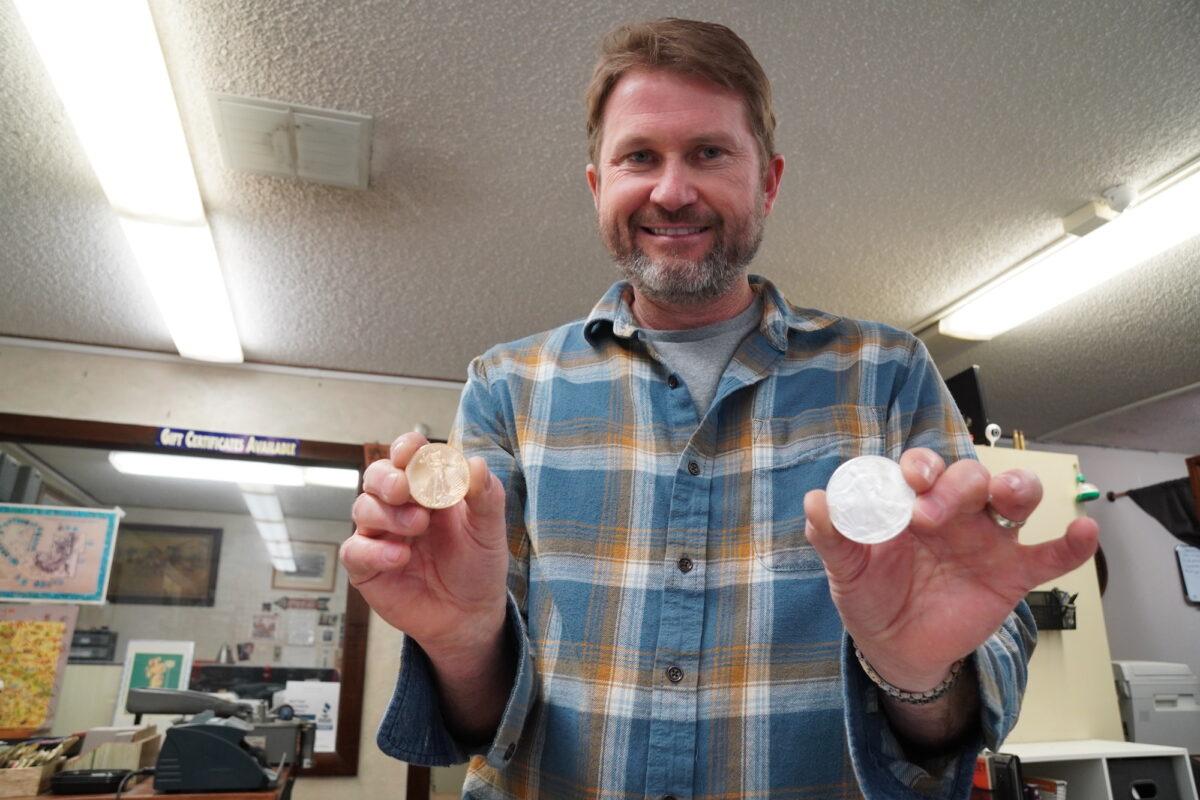 Gabe Wright, co-owner of Coin Heaven in Cottonwood, Ariz., holds gold and silver coins, two of the hottest-selling items on March 20, 2023. (Allan Stein/The Epoch Times)