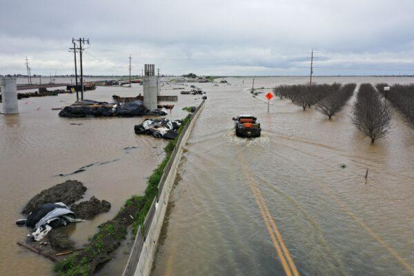 This aerial image shows a truck as it drives across a flooded road past Central Valley farmland along the Tule River in Tulare County during a winter storm near Corcoran, Calif., on March 21, 2023. (Patrick T. Fallon/AFP via Getty Images)