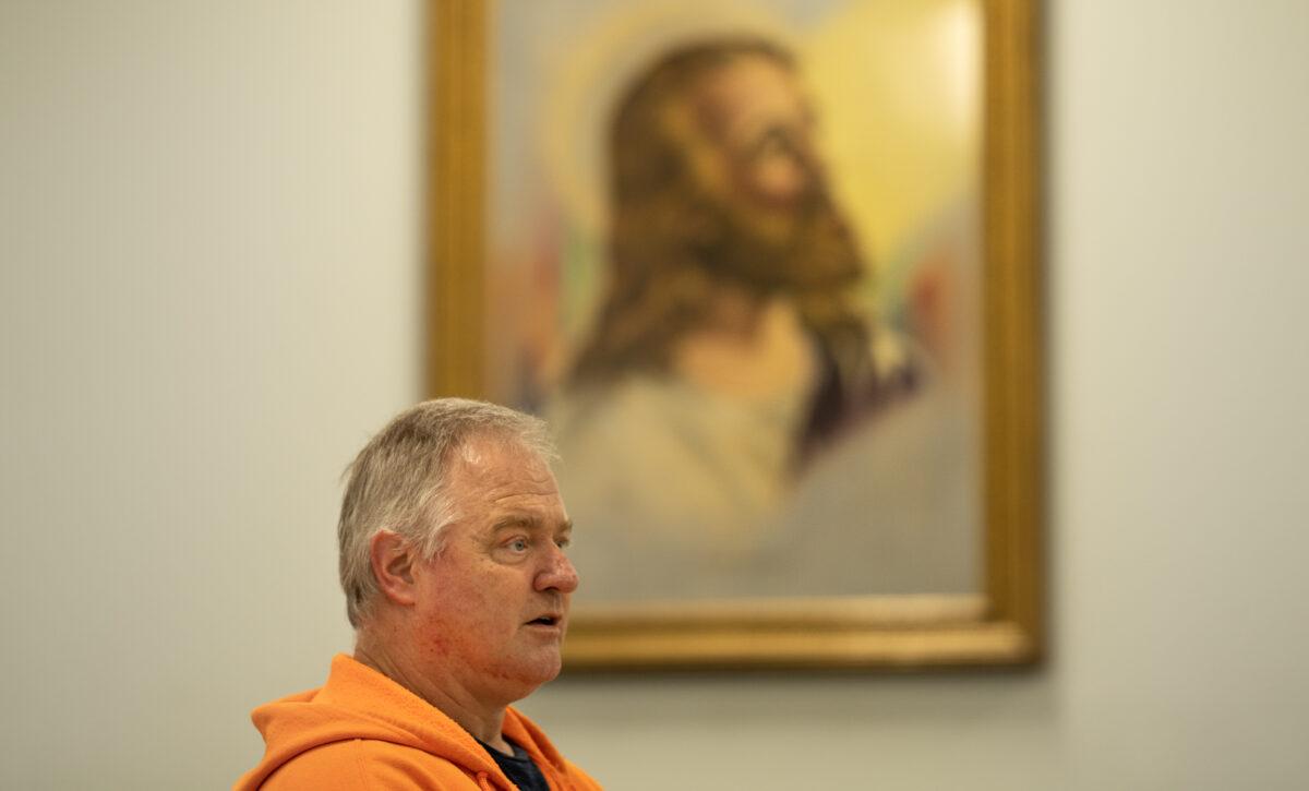 Brett Boman sits under a painting of Jesus in the Salvation Army chapel where he was able to recover from drug addiction in Chico, Calif., on March 12, 2023. (John Fredricks/The Epoch Times)