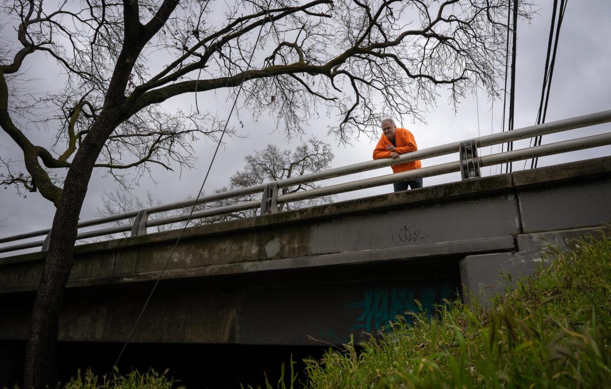 Brett Boman stands over a bridge he used to sleep under while homeless in Chico, Calif., on March 12, 2023. (John Fredricks/The Epoch Times)