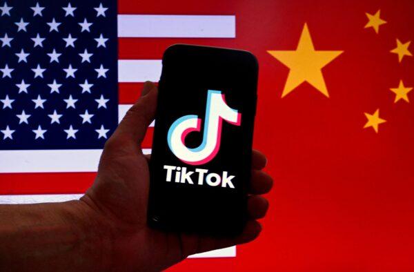 The social media application logo for TikTok—owned by Chinese company Bytedance—is displayed on the screen of an iPhone in front of a U.S. flag and Chinese flag background in Washington on March 16, 2023. (Olivier Douliery/AFP via Getty Images)