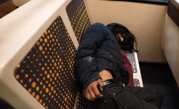 A homeless man sleeps on a Metro train in Los Angeles on April 19, 2023. (John Fredricks/The Epoch Times)