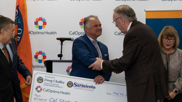 Officials from CalOptima, which offers public health insurance in Orange County, present a $5 million check to California State University–Fullerton to support students pursuing a master’s degree in the school’s social worker program at a press conference in Fullerton, Calif., on May 15, 2023. (Courtesy of CalOptima)