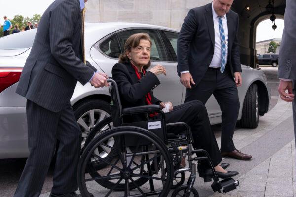 Sen. Dianne Feinstein (D-Calif.) is assisted in a wheelchair by staff as she returns to the Senate after a months-long absence, at the Capitol on May 10, 2023. (J. Scott Applewhite/AP Photo)