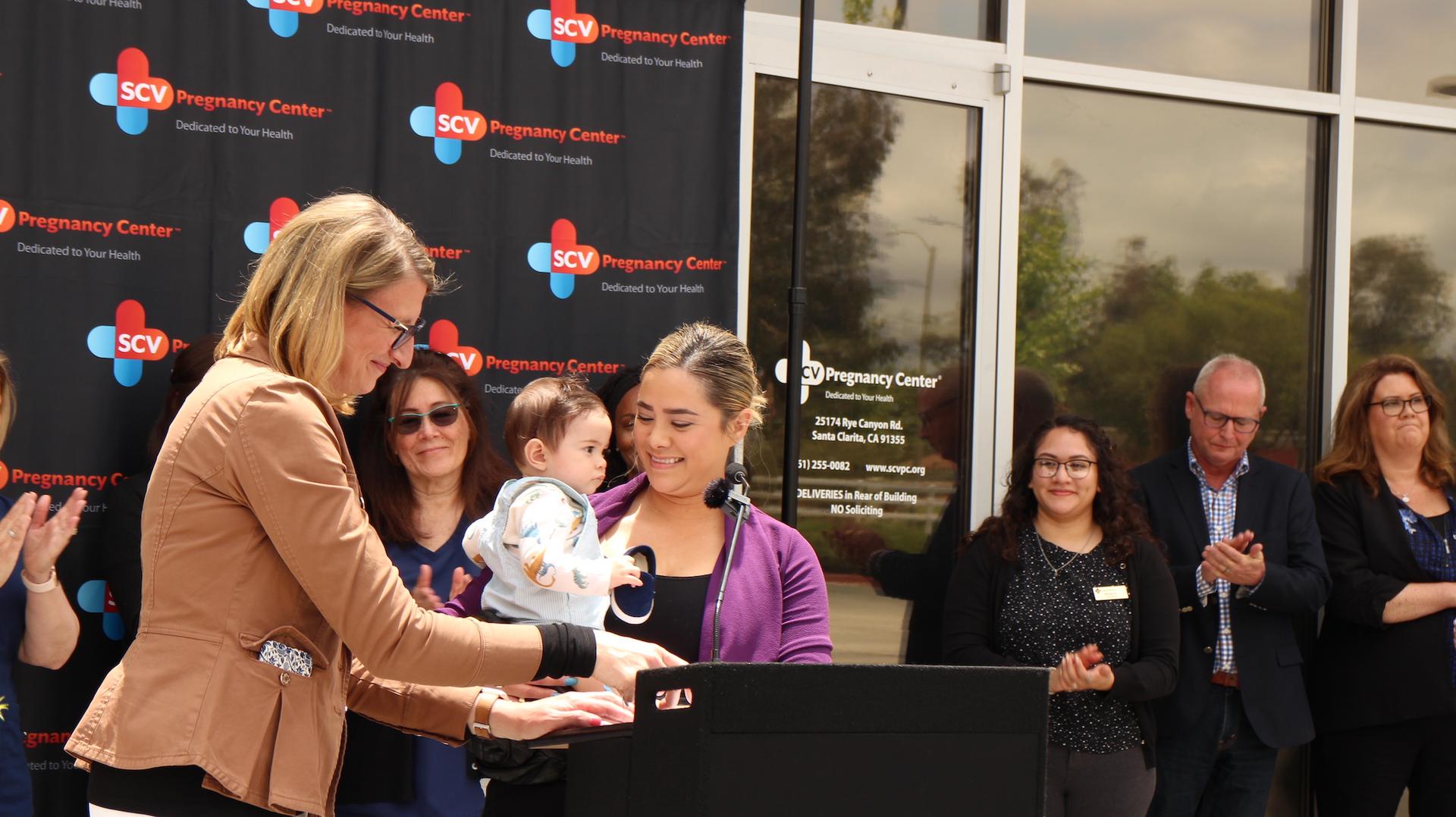 A patient of the Santa Clarita Valley Pregnancy Center, holding her son, speaks during a press conference in Santa Clarita, Calif., on May 24, 2023. (Courtesy of California Family Council)