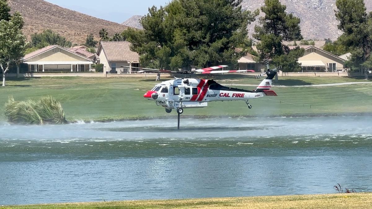 A Cal Fire Type 2 helicopter draws water from the golf course at Menifee Lakes Country Club to extinguish a brush fire in Menifee, Calif., on June 20, 2023. These helicopters, which are smaller than the Type 1 aircraft, typically carry about 300 gallons of water, according to the National Interagency Fire Center. (Brad Jones/The Epoch Times)