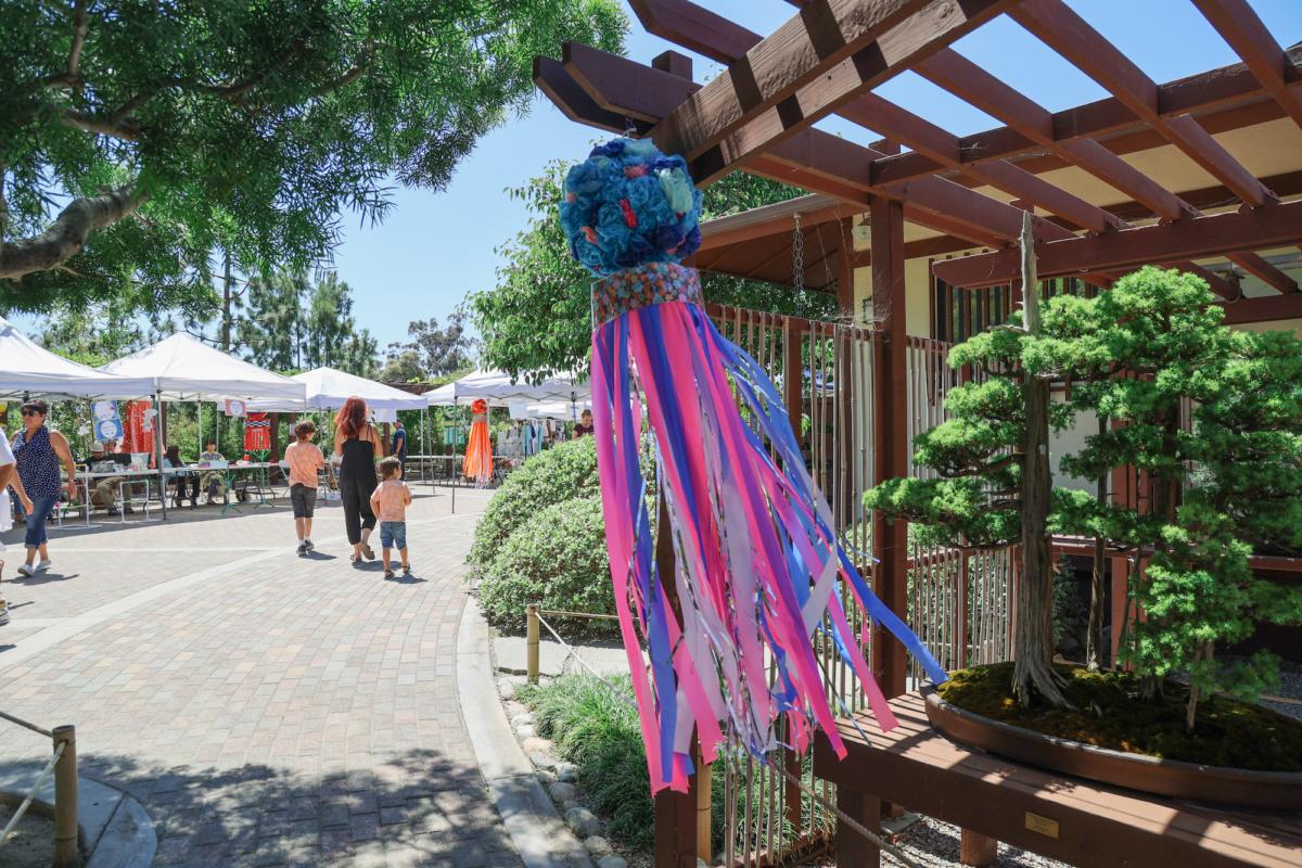 A Fukinagashi, streamer decorations of fabric, hangs over bonsai trees at the Tanabata Festival in the Balboa Park Japanese Friendship Garden in San Diego on July 7, 2023. (Julianne Foster/The Epoch Times)
