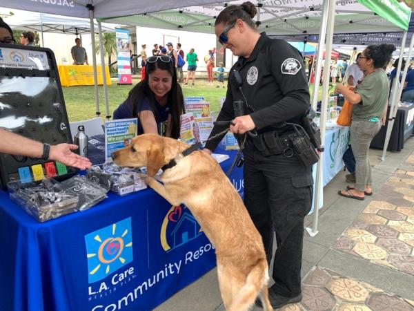 A police officer and her K9 officer interacts with a local organization at a National Night Out event at Pomona Civic Center in Pomona, Calif., on Aug. 1, 2023. (Linda Jiang/The Epoch Times)