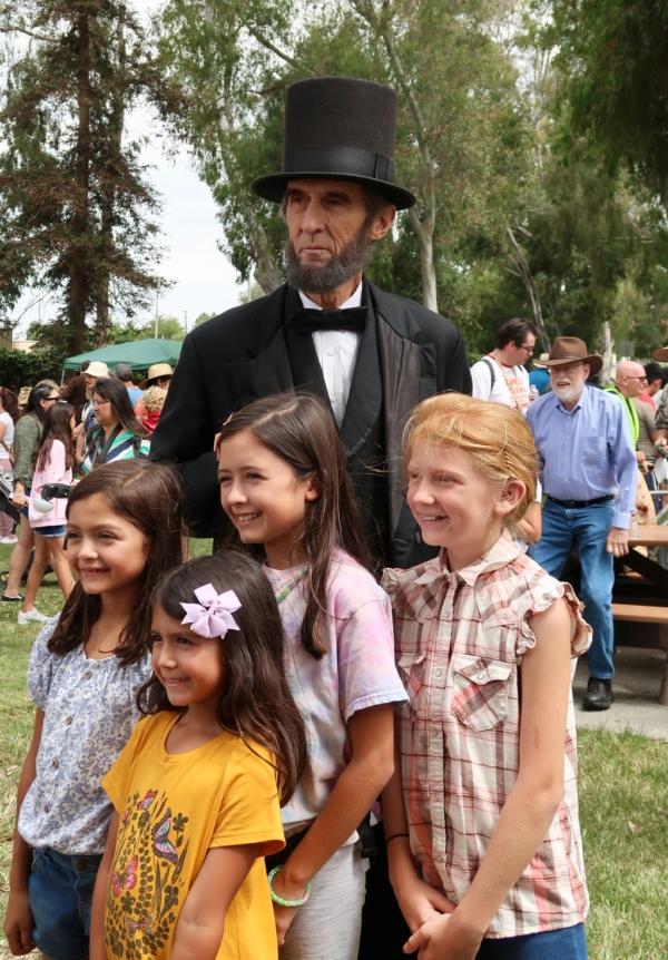 The Abraham Lincoln reenactor poses for a picture with children during the 30th annual Civil War Days event at Huntington Beach Central Park in Huntington Beach, Calif., on Sept. 3, 2023. (Sophie Li/The Epoch Times)