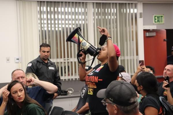 A member of the Revolutionary Communist Party opposing a school district policy to notify parents when their child wishes to identify as transgender shouts into a megaphone at an Orange Unified School Board meeting in Orange, Calif., on Sept. 7, 2023. (Mei Lee/The Epoch Times)