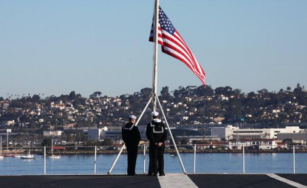 U.S. Navy sailors prepare to take down the flag on the flight deck of the USS Nimitz aircraft carrier in Coronado, Calif., on Jan. 18, 2020. (Mario Tama/Getty Images)