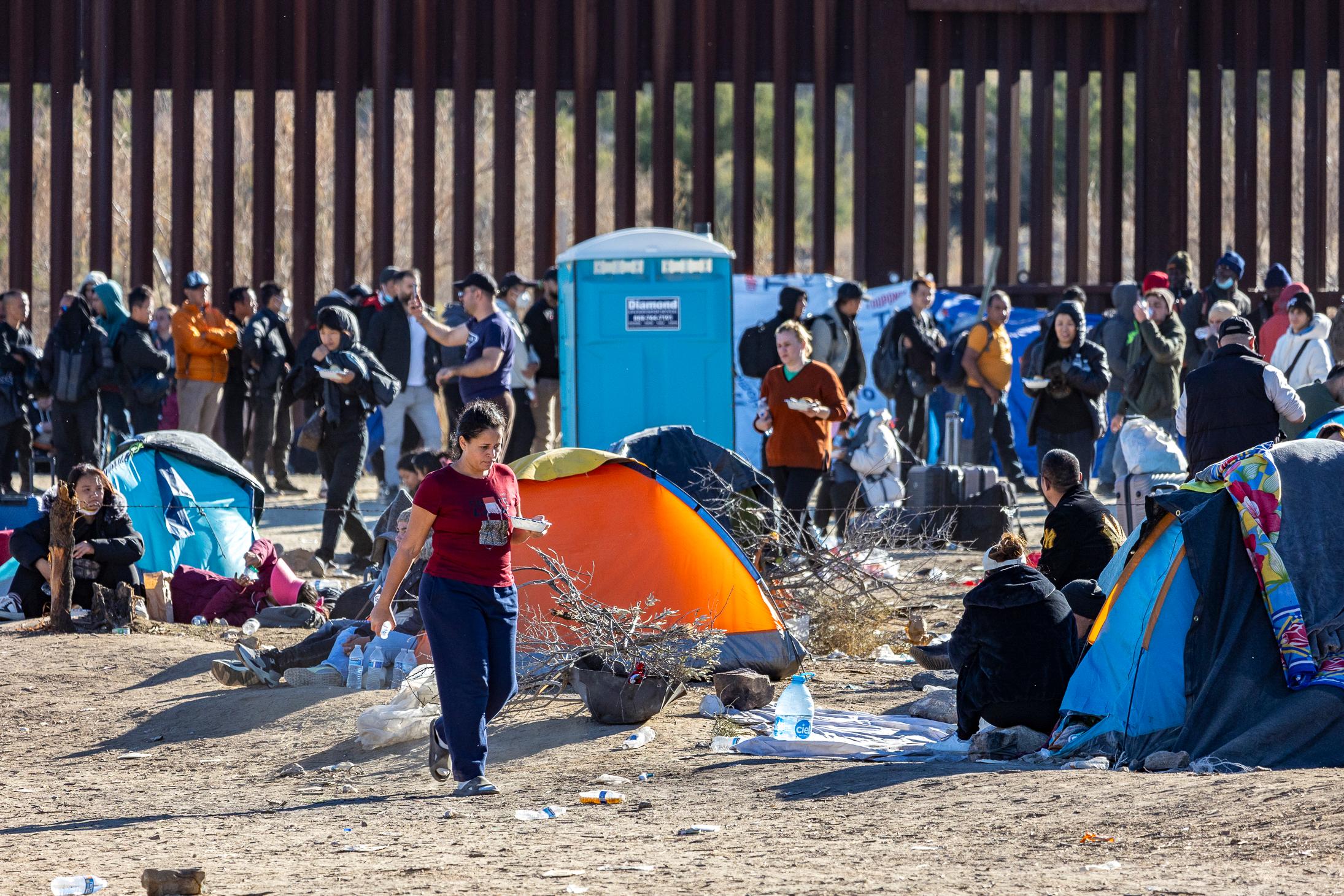 Illegal immigrants who passed through a gap in the U.S. border wall await processing by Border Patrol agents in Jacumba, Calif., on Dec. 7, 2023. (John Fredricks/The Epoch Times)