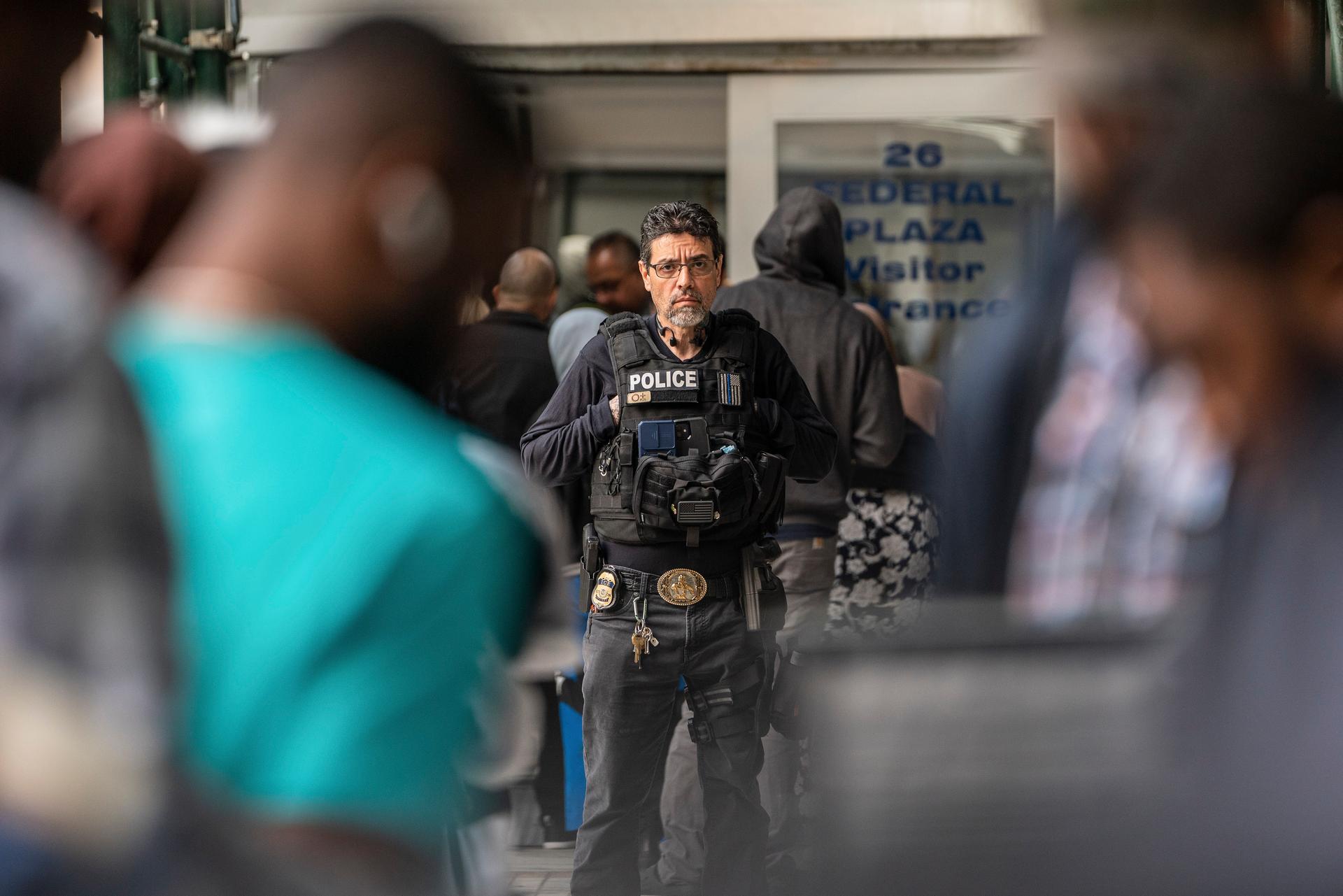 An Immigration and Customs Enforcement agent monitors hundreds of asylum seekers being processed upon entering the Jacob K. Javits Building in New York City on June 6, 2023. (David Dee Delgado/Getty Images)