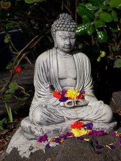 The original Buddha statue before it was painted, sitting on the ground with flower offerings. (Courtesy of Dan Stevenson)