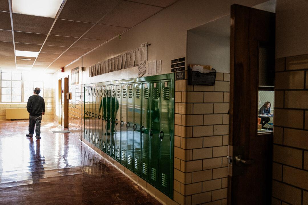 A teacher walks down an empty hallway while another teaches virtually (R) at Hazelwood Elementary School in Louisville, Ky., on Jan. 11, 2022. (Jon Cherry/Getty Images)