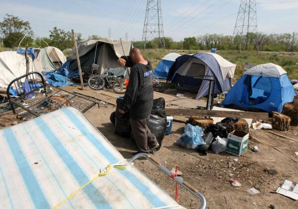 A homeless man wipes his forehead as he packs belongings at a tent city in Sacramento on April 13, 2009. (Justin Sullivan/Getty Images)