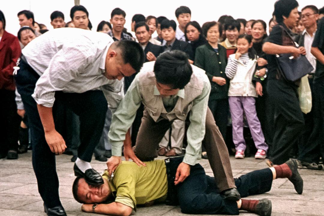 Chinese police detain a Falun Gong practitioner as a crowd gathers around in Tiananmen Square in Beijing on Oct. 1, 2000. (Chien-Min Chung/AP Photo)