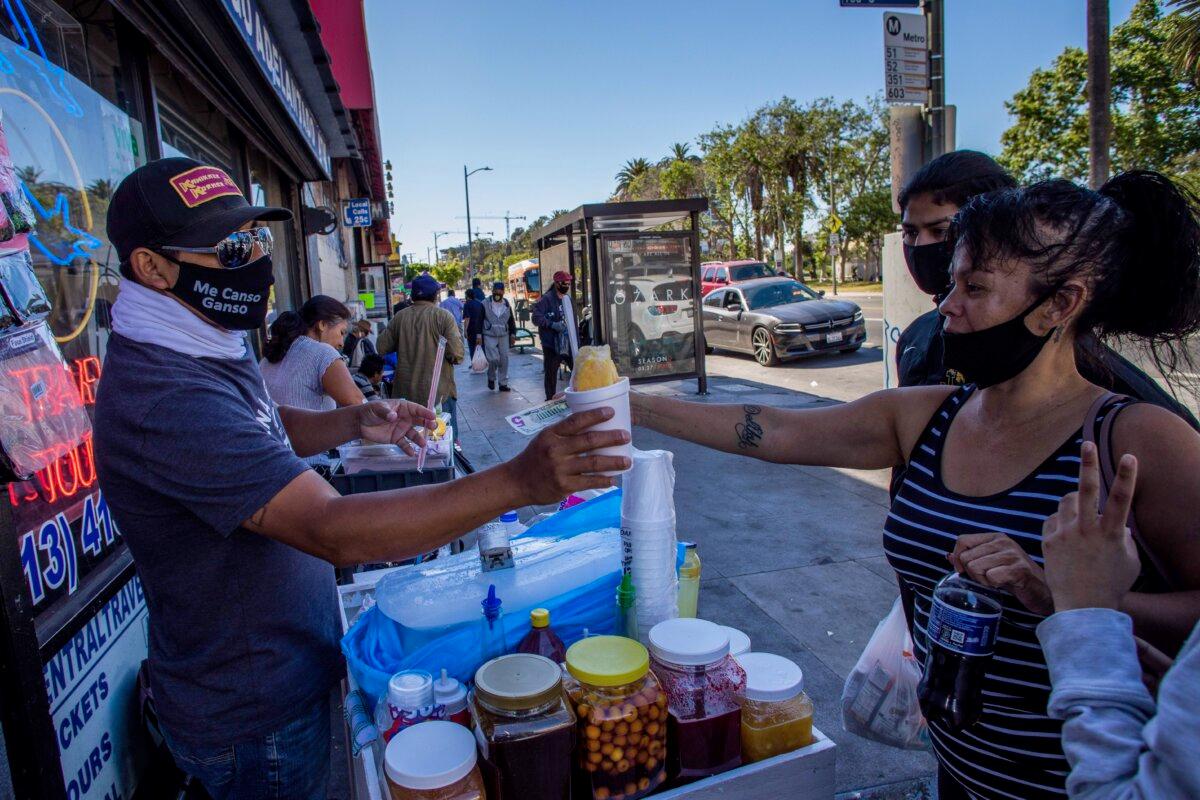 A street vendor sells a snow cone to customers in MacArthur Park in Los Angeles on May 21, 2020. (Apu Gomes/AFP via Getty Images)