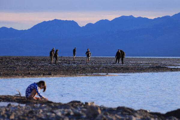 A kid plays with water as tourists enjoy the rare opportunity to see water as they visit Badwater Basin, the normally driest place in the US, in Death Valley National Park, Inyo County, Calif., on Feb. 18, 2024. (David Swanson/AFP via Getty Images)