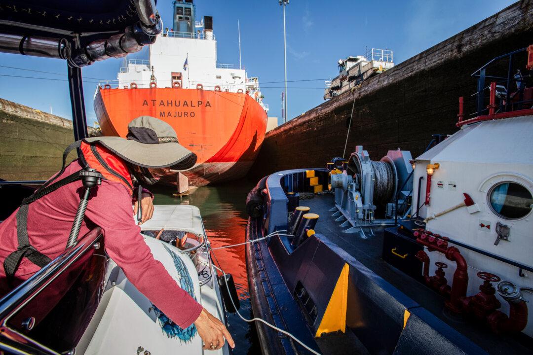 Workers secure lines on a boat as it follows a ship into the Panama Canal on Feb. 21, 2024. (Bobby Sanchez for The Epoch Times)