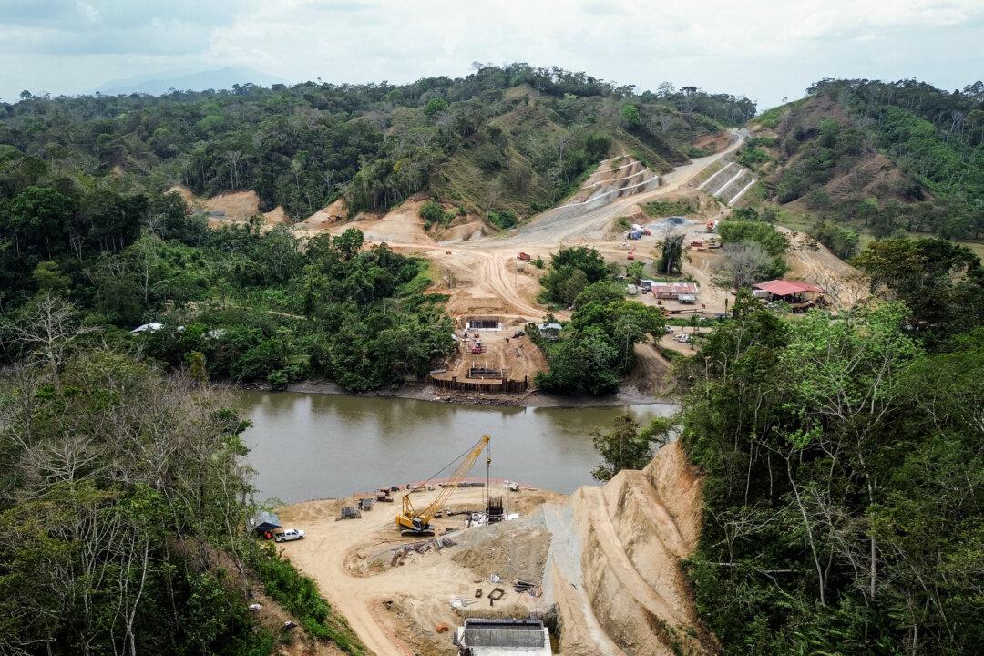 Workers prepare abutments for a bridge spanning the Chucunaque River at Yaviza, Panama, on Feb. 20, 2024. An onsite worker for the construction company Cusa said the project will cut four miles into the Darién jungle at a cost of $42 million and includes a second bridge crossing the Tuira River. (Bobby Sanchez for The Epoch Times)