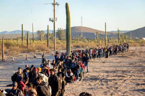 Illegal immigrants line up at a remote U.S. Border Patrol processing center after crossing the U.S.–Mexico border, in Lukeville, Ariz., on Dec. 7, 2023. (John Moore/Getty Images)