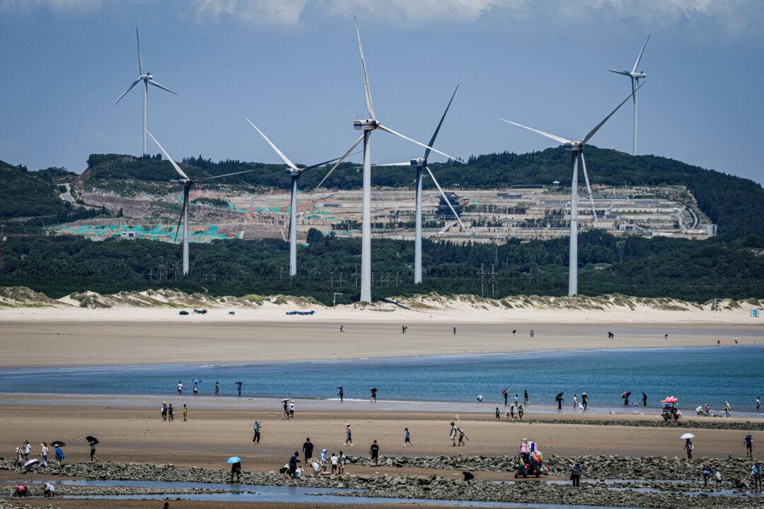 Beachgoers walk near wind turbines along the coast of Pingtan in Southern China's Fujian Province on Aug. 6, 2022. (Ng Han Guan/AP Photo, File)