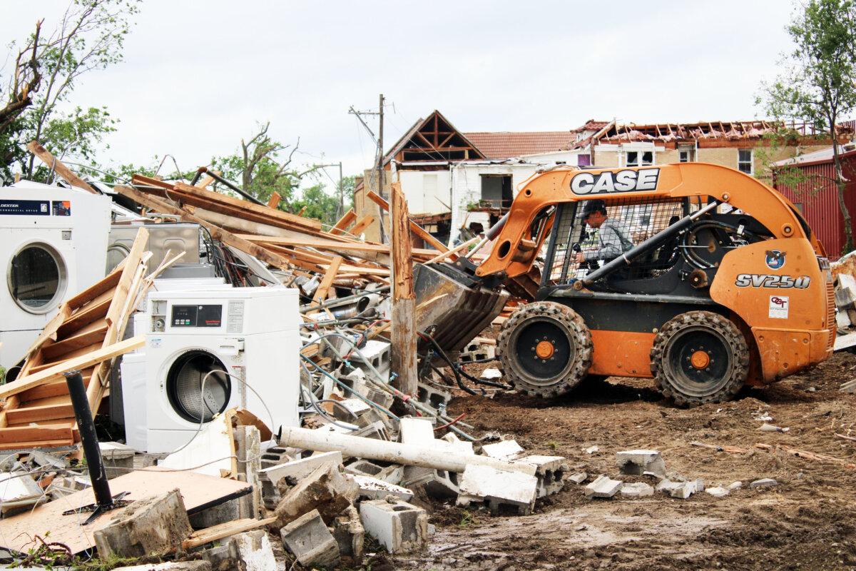 Les Kirby uses a skid-steer loader to remove debris from his coin laundry business in Sulphur, Okla., on April 28, 2024. (Michael Clements/The Epoch Times)