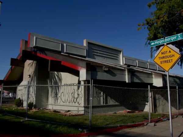 A closed Denny's restaurant on Hegenberger Road is covered in graffiti, with a homeless encampment adjacent to it. (Travis Gillmore/The Epoch Times)