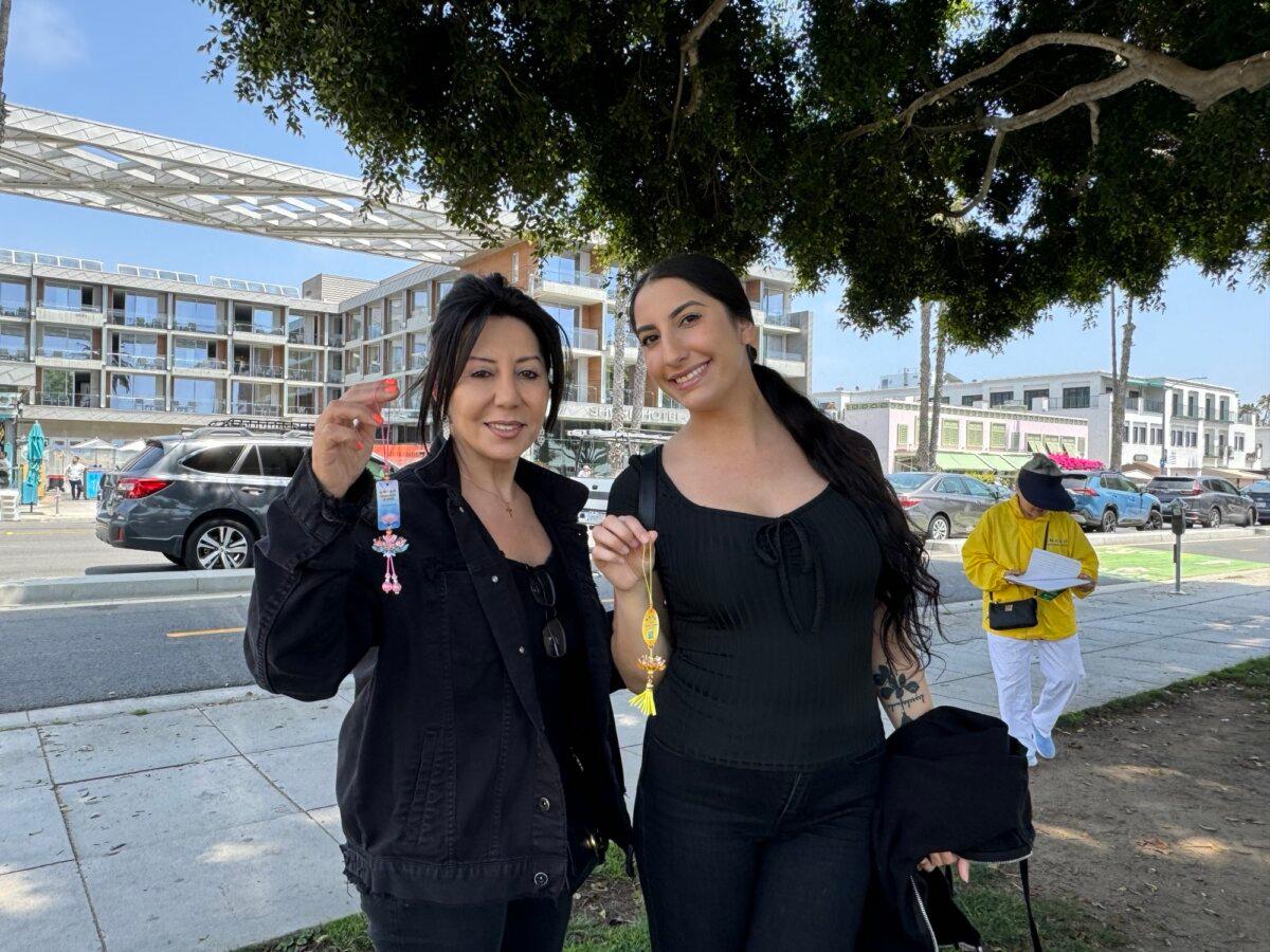 Two visitors hold up lotus flower decorations at the 25th celebration of Falun Dafa Day in Santa Monica, Calif., on May 12, 2024. (Linda Jiang/The Epoch Times)