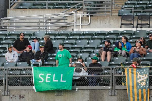 Fans watch from behind a sign calling for Oakland A's management to sell the team during a game against the Pittsburgh Pirates in Oakland, Calif., on April 29, 2024. (Jeff Chiu/AP Photo)