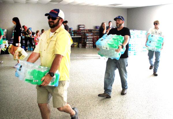 Volunteers carry cases of bottled water into the Valley View, Texas, community center on May 16, 2024. (Michael Clements/The Epoch Times)