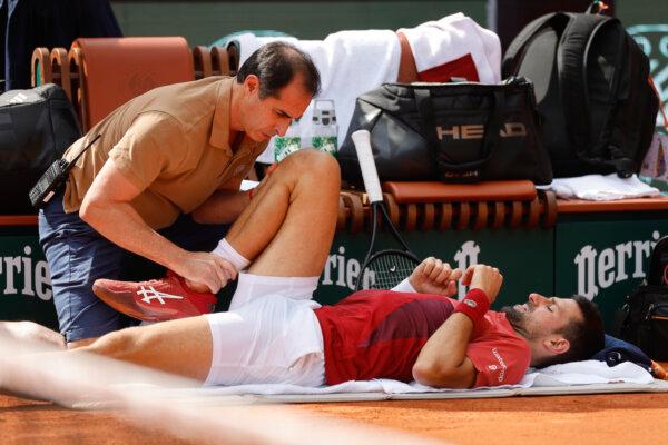 Novak Djokovic receives medical assistance after suffering a knee injury during the French Open in Paris on June 3, 2024. (Jean-Francois Badias/AP Photo)