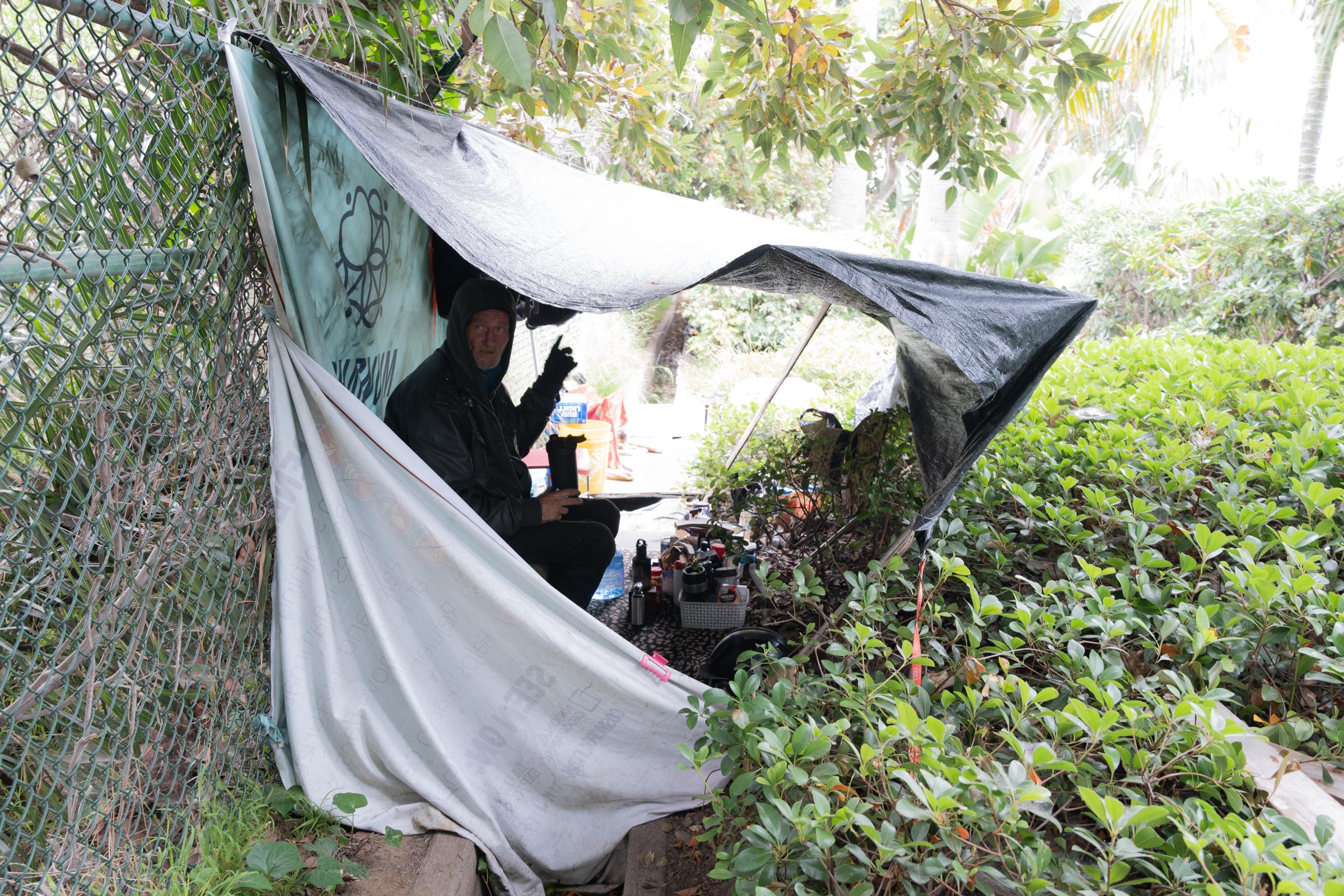 A homeless person sits in his tent just outside the H Barracks site. (Jane Yang/The Epoch Times)