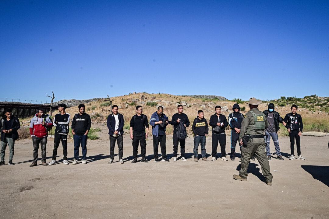 A Border Patrol agent apprehends a large group of mostly Chinese illegal immigrants who crossed the U.S.–Mexico border, at Jacumba, Calif., on June 6, 2024. Since October 2023, border agents have already apprehended 48,500 Chinese illegal immigrants. (Frederic J. Brown/AFP via Getty Images)