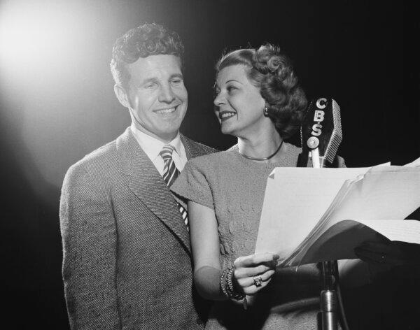 American actor, screenwriter and bandleader Ozzie Nelson and his wife, American actress and singer Harriet Nelson, who holds pages of a script as the two stand smiling before a CBS microphone as they record their radio sitcom "The Ozzie Nelson-Harriet Hilliard Show," circa 1945. (Graphic House/Archive Photos/Getty Images)