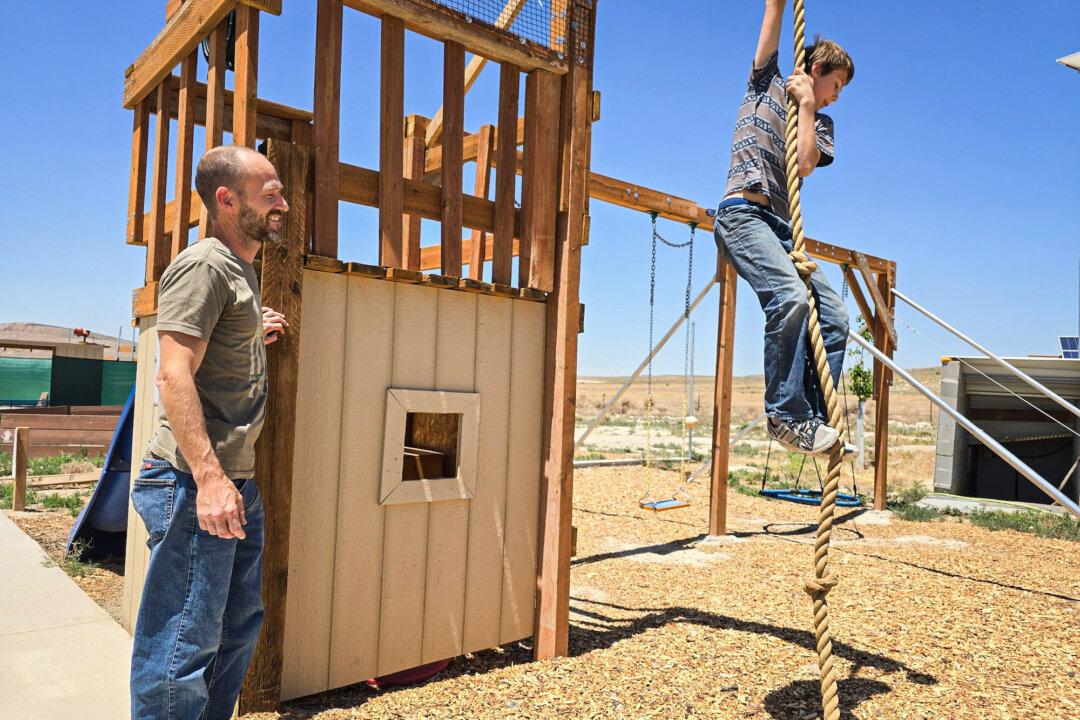 (Top) Brandon Wilson stands next to the solar panel array that will power his family's new home at Operation Self-Reliance in Utah on June 28, 2024. (Bottom) Brandon Wilson watches his son Bron, 13, climb a rope on June 28, 2024. (Allan Stein/The Epoch Times)