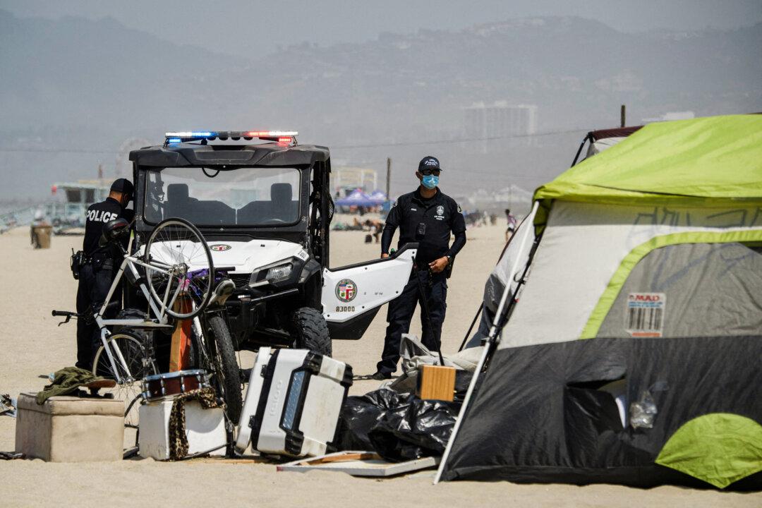 Police officers approach a tent belonging to a homeless person on Venice Beach in Los Angeles on June 16, 2021. (Patrick T. Fallon/AFP via Getty Images)