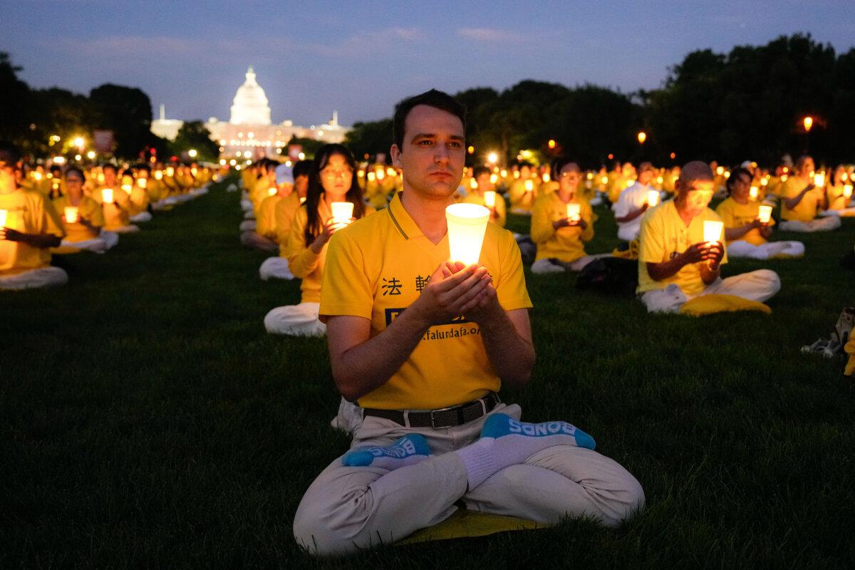 Falun Gong adherents take part in a candlelight vigil in memory of Falun Gong practitioners who passed away during 25 years of ongoing persecution by the Chinese Communist Party in China at the National Mall in Washington on July 11, 2024. (Larry Dye/The Epoch Times)