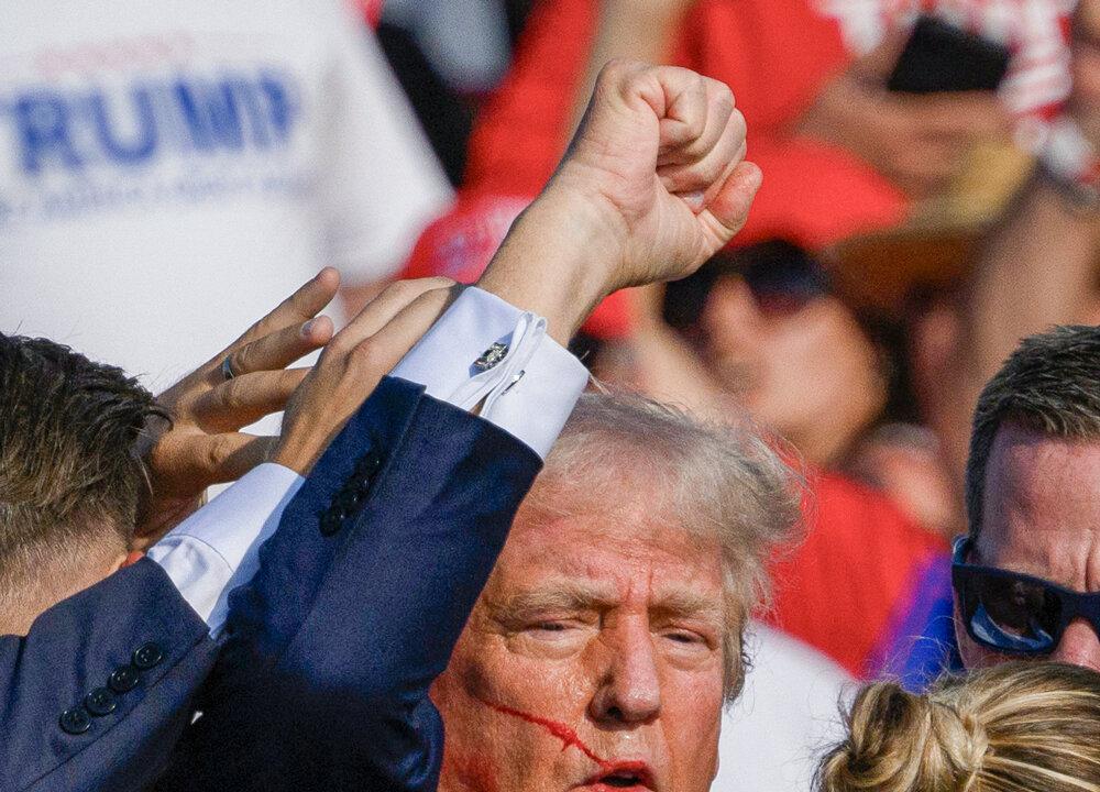 U.S. Secret Service agents rush to protect former President Donald Trump after shots were fired at him. As the former president stands up, he raises his fist to the crowd, and says, “Fight, fight, fight!” (Evan Vucci/AP Photo, Jeff Swensen/Getty Images)