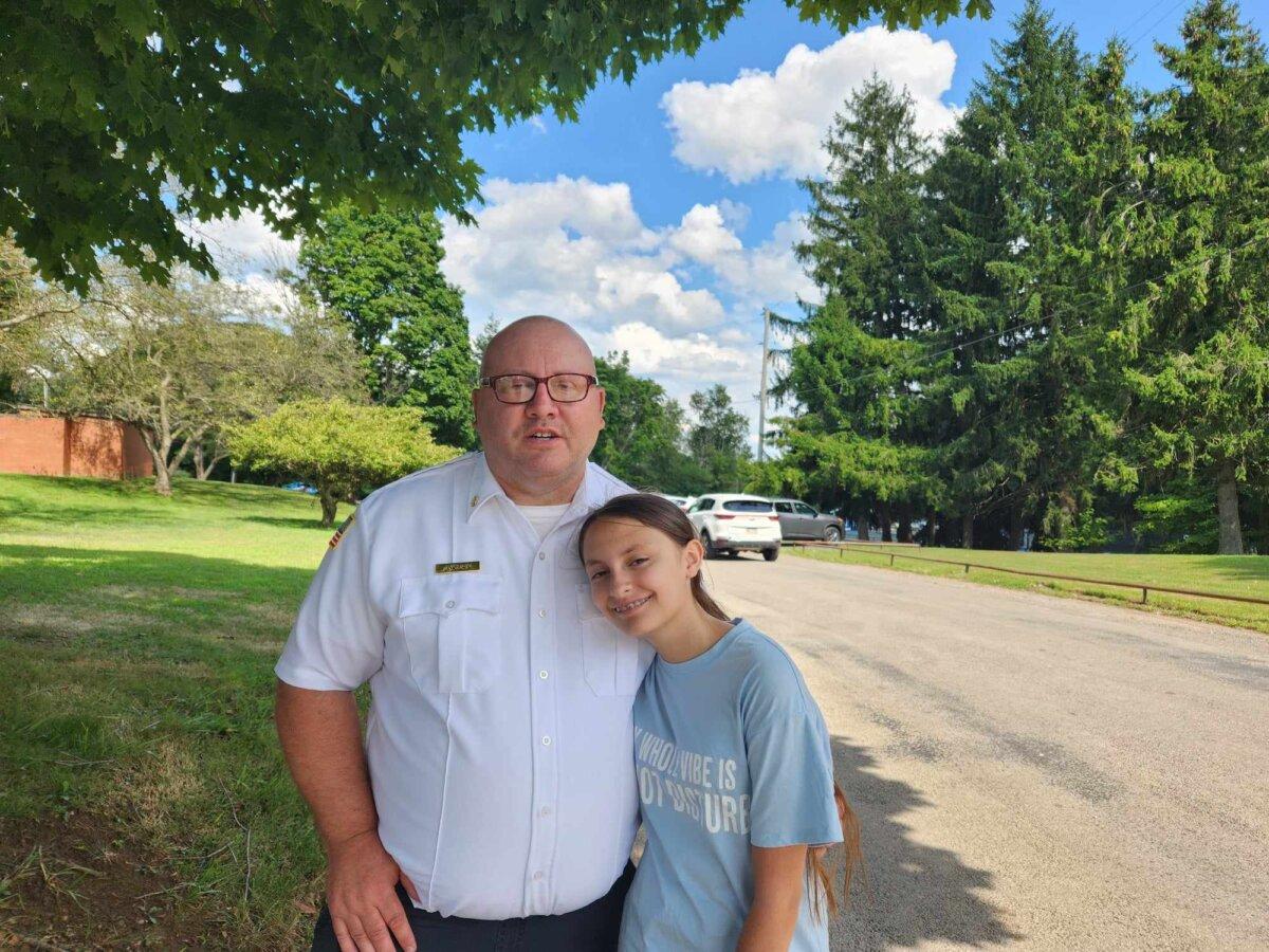 Former fire chief James Kuhn and his 12-year-old daughter, Isabella, paid their respects to Corey Comperatore in Freeport, Pa. on July 18, 2024. (Jeff Louderback/Epoch Times)