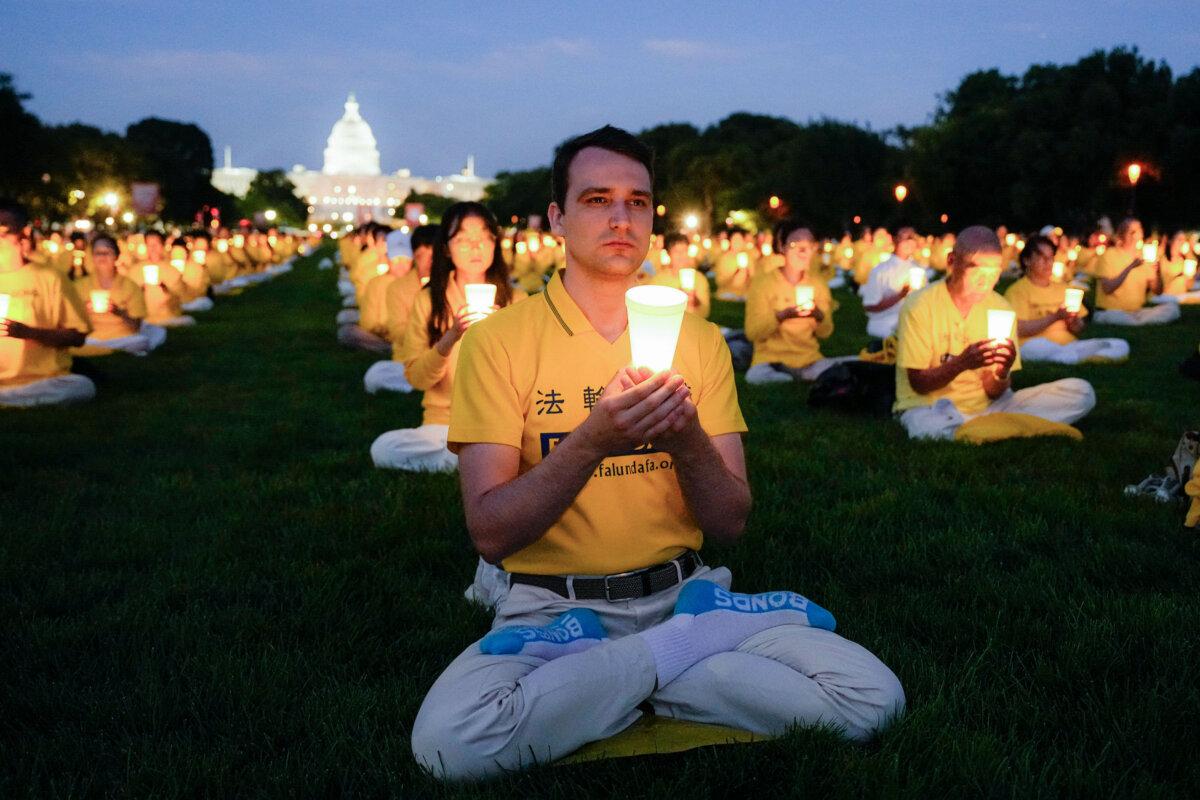 Falun Gong practitioners take part in a candlelight vigil in memory of Falun Gong practitioners who passed away during 25 years of ongoing persecution by the Chinese Communist Party in China at the National Mall in Washington on July 11, 2024. (Larry Dye/The Epoch Times)