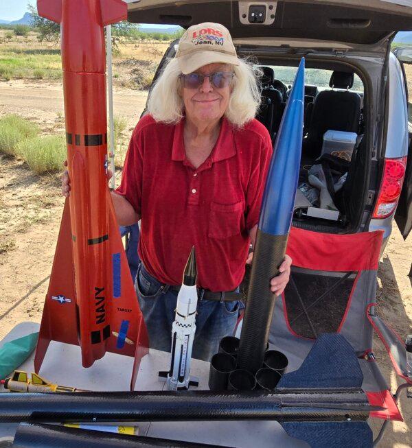 Terry Gilpin, a member of the Southern Arizona Rocketry Association (SARA), stands with three model rockets he built during a monthly club launch in Marana, Ariz., on Feb. 15, 2024. (Allan Stein/The Epoch Times)