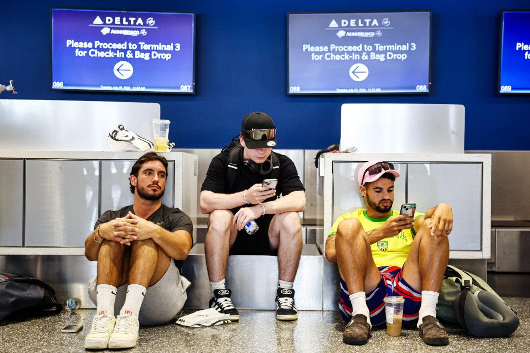 Travelers wait for their delayed flight, in the aftermath of the CrowdStrike outage, by the check-in counter at Los Angeles International Airport on July 23, 2024. (Mario Tama/Getty Images)