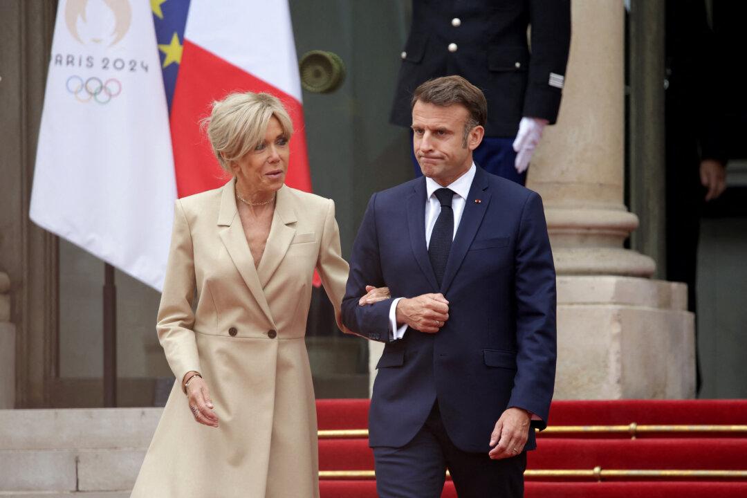 French President Emmanuel Macron (R) and his wife, Brigitte Macron (L), stand at Elysee presidential palace court before a reception given for heads of state and governments ahead of the opening ceremony of the Paris 2024 Olympic Games in Paris on July 26, 2024. (Valentine Chapuis/AFP via Getty Images)