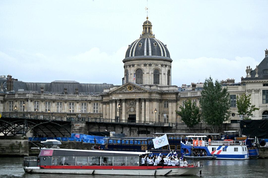 Athletes from the Refugee Olympic Team's delegation sail in a boat along the river Seine, past the Pont des Arts footbridge and the Institut de France during the opening ceremony of the Paris 2024 Olympic Games in Paris on July 26, 2024. (Kirill Kudryavtsev/AFP via Getty Images)